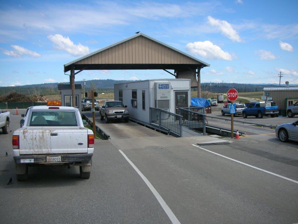 An overhang sits between two alternating pathways.Under the overhang is a trailer with a paved ramp in front of it.
